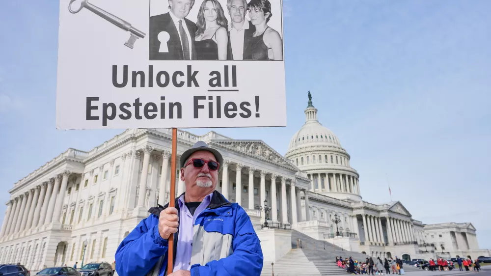 Gary Rush, College Park, MD, holds a sign before a news conference on the Epstein files in front of the Capitol, Tuesday, Nov. 18, 2025, in Washington. (AP Photo/Mariam Zuhaib)