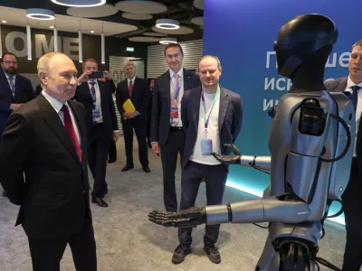 Russian President Vladimir Putin, left, looks at a humanoid robot with built-in Sberbank's GigaChat as he visits an exhibition of the AI Journey 2025, an international conference on artificial intelligence and machine learning, at the Sberbank City business complex in Moscow, Russia, Wednesday, Nov. 19, 2025. (Vyacheslav Prokofyev, Sputnik, Kremlin Pool Photo via AP)