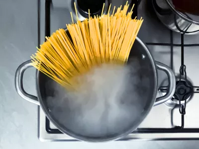 Cooking raw spaghetti in the boiling water contained in a saucepan. Italian cuisine. Raw food. interior of a domestic kitchen. Food preparation and cooking / Foto: Rarrarorro