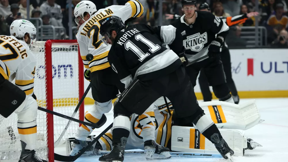 Nov 21, 2025; Los Angeles, California, USA; Los Angeles Kings center Anze Kopitar (11) fighst for the puck against Boston Bruins defenseman Hampus Lindholm (27) during the second period at Crypto.com Arena. Mandatory Credit: Kiyoshi Mio-Imagn Images