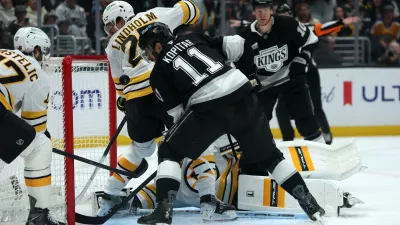 Nov 21, 2025; Los Angeles, California, USA; Los Angeles Kings center Anze Kopitar (11) fighst for the puck against Boston Bruins defenseman Hampus Lindholm (27) during the second period at Crypto.com Arena. Mandatory Credit: Kiyoshi Mio-Imagn Images
