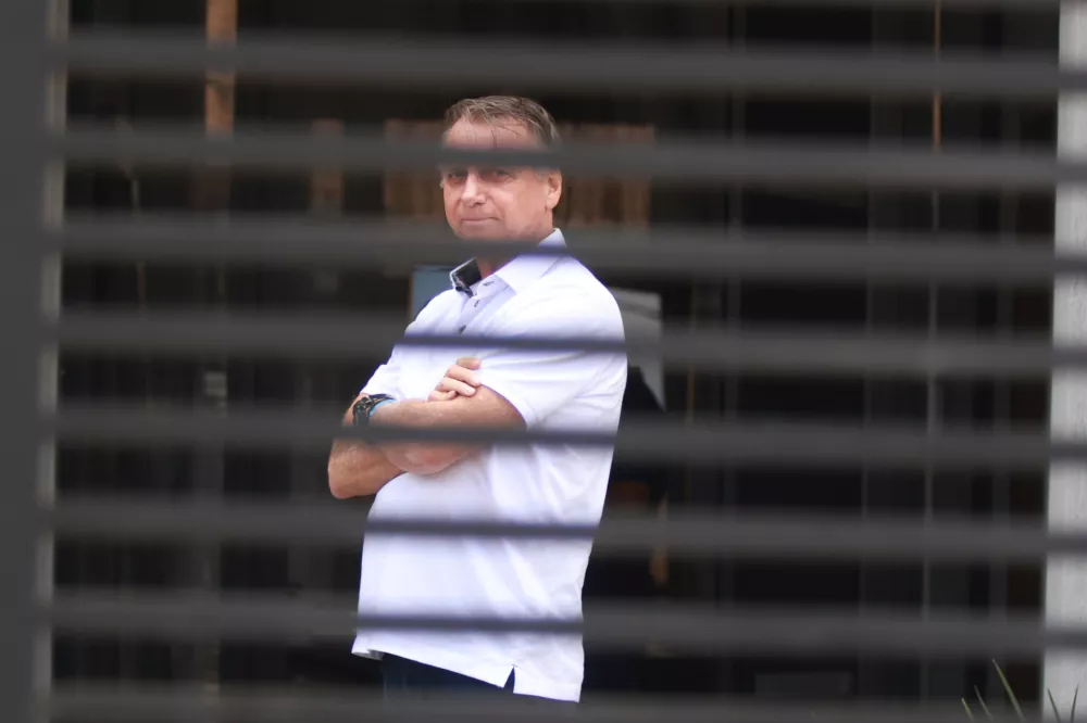 FILE - Brazil's former President Jair Bolsonaro stands at the entrance of his home where he is under house arrest in Brasilia, Brazil, Tuesday, Sept. 2, 2025. (AP Photo/Luis Nova, File)