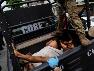 EDS NOTE: GRAPHIC CONTENT - A police officer stands over bloodied people lying in the back of a police truck brought to the Getulio Vargas Hospital during a police operation against alleged drug traffickers in the Complexo do Alemao favela where the criminal organization "Comando Vermelho" operates in Rio de Janeiro, Tuesday, Oct. 28, 2025. (AP Photo/Silvia Izquierdo)