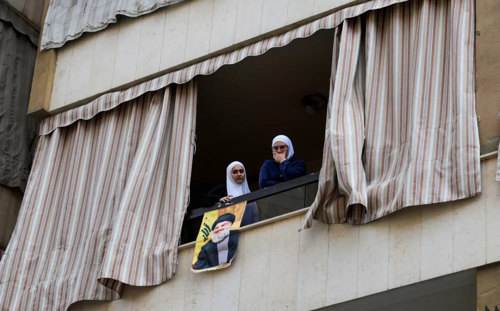 Women stand on a balcony at the site of an Israeli strike that happened yesterday on a building, after what the Israeli military said was an airstrike that killed Hezbollah's top military official, following a U.S.-brokered truce a year ago, in Beirut's southern suburbs, Lebanon November 24, 2025. REUTERS/Mohamed Azakir 
