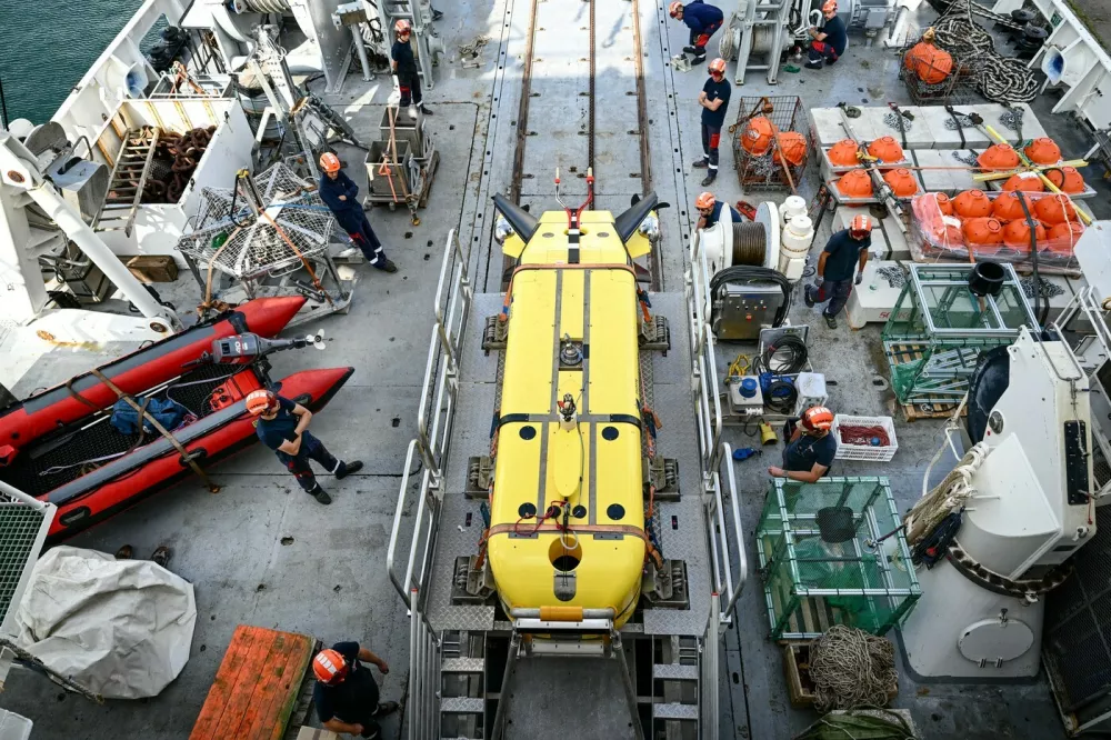 Technicians carry out a test launch of the underwater robot Ulyx aboard the scientific ship ATALANTE docked at the port of Brest before its departure, in Brest, western France, on June 15, 2025. Between 1950 and 1990, more than 200,000 barrels filled with radioactive waste were thrown into the abyss of the Northeast Atlantic Ocean. The first mission of the NODSSUM campaign, planned from June 15 to July 11, 2025 and led by the French National Centre for Scientific Research (CNRS), aims to map the main barrel immersion area and study interactions with marine biodiversity.,Image: 1011220224, License: Rights-managed, Restrictions:, Model Release: no