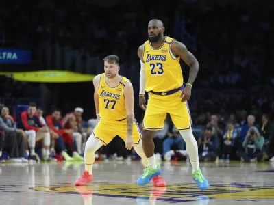 Los Angeles Lakers' LeBron James (23) and Luka Doncic (77) watch action during the second half of an NBA basketball game against the New Orleans Pelicans Tuesday, March 4, 2025, in Los Angeles. (AP Photo/Jae C. Hong)