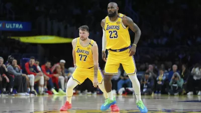 Los Angeles Lakers' LeBron James (23) and Luka Doncic (77) watch action during the second half of an NBA basketball game against the New Orleans Pelicans Tuesday, March 4, 2025, in Los Angeles. (AP Photo/Jae C. Hong)