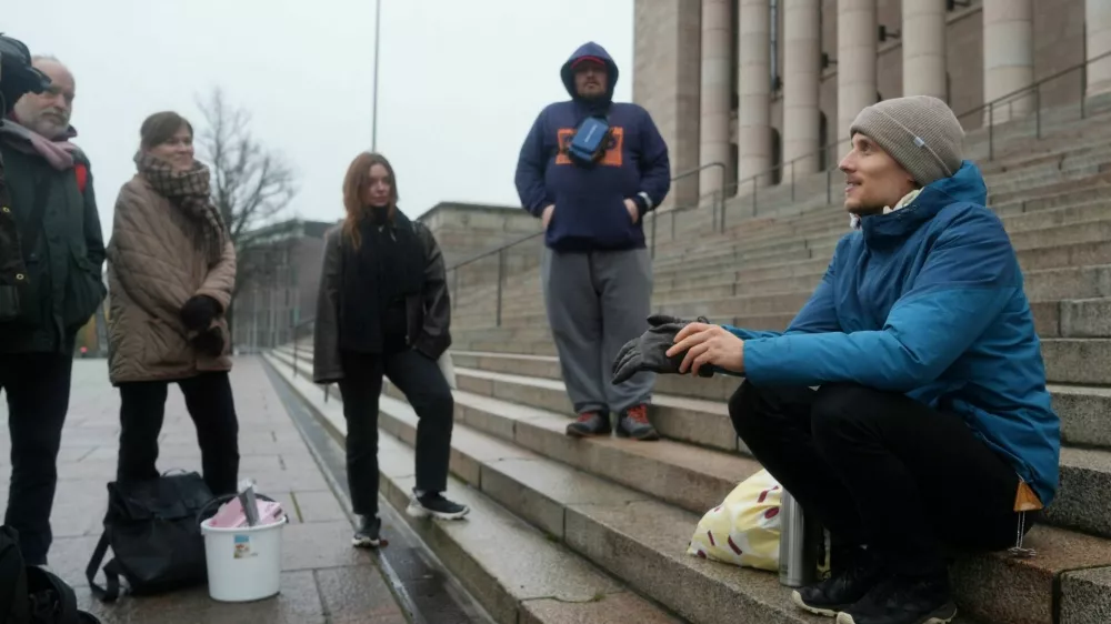 Juho-Pekka Palomaa, 33, sits on the steps in front of the Finnish parliament where he was holding a potluck protest to mark 1000 days of unemployment, in Helsinki, Finland, October 30, 2025. REUTERS/Tom Little