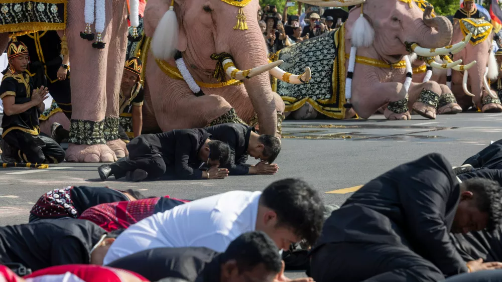 People bow as elephant riders lead a procession of white elephants for the late Queen Mother Sirikit along the Grand Palace in Bangkok, Thailand, Thursday, Nov. 27, 2025. (AP Photo/Wason Wanitchakorn)