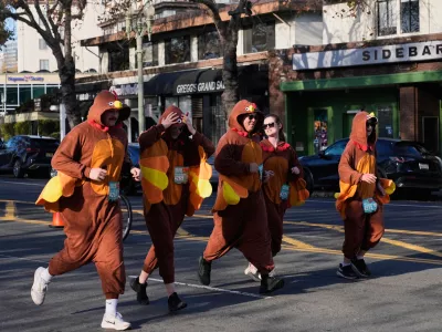 A group of people wearing turkey costumes run during the Oakland Turkey Trot in Oakland, Calif., Thursday, Nov. 27, 2025. (AP Photo/Godofredo A. Vásquez)