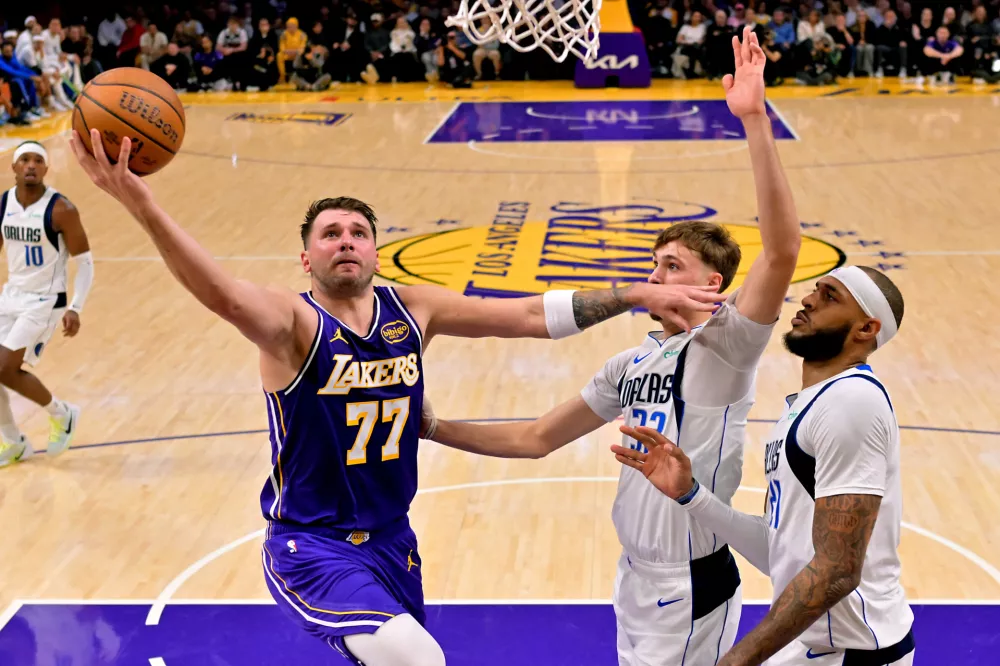 Nov 28, 2025; Los Angeles, California, USA; Los Angeles Lakers guard Luka Doncic (77) drives past Dallas Mavericks forward Cooper Flagg (32) and forward Daniel Gafford (21) in the first half at Crypto.com Arena. Mandatory Credit: Jayne Kamin-Oncea-Imagn Images