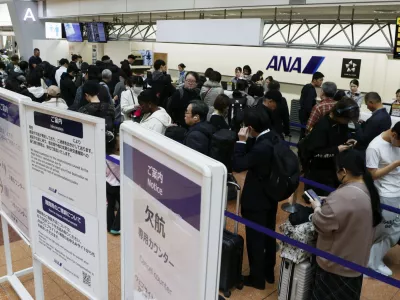 Passengers wait in line at All Nippon Airways' counter at Haneda airport in Tokyo Saturday, Nov. 29, 2025. A sign, right, reads " Flight cancellation counter." (Takahiko Kanbara/Kyodo News via AP)