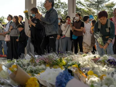 People pray and lay flowers near the site of the deadly Wednesday fire at Wang Fuk Court, a residential estate in the Tai Po district of Hong Kong's New Territories on Saturday, Nov. 29, 2025. (AP Photo/Ng Han Guan)