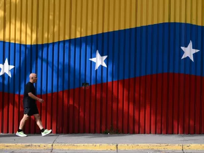 A man walks past a mural with the colors of the Venezuelan flag, after U.S. President Donald Trump said on Saturday that the airspace above and around Venezuela would be completely closed, amid rising tensions between the Trump administration and the government of Venezuelan President Nicolas Maduro, in Caracas, Venezuela, November 29, 2025. REUTERS/Gaby Oraa