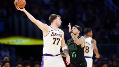 Los Angeles Lakers guard Luka Doncic (77) holds the ball against New Orleans Pelicans guard Jose Alvarado (15) as Los Angeles Lakers forward Rui Hachimura, right, runs during the first half of an NBA basketball game, Sunday, Nov. 30, 2025, in Los Angeles. (AP Photo/Jessie Alcheh)