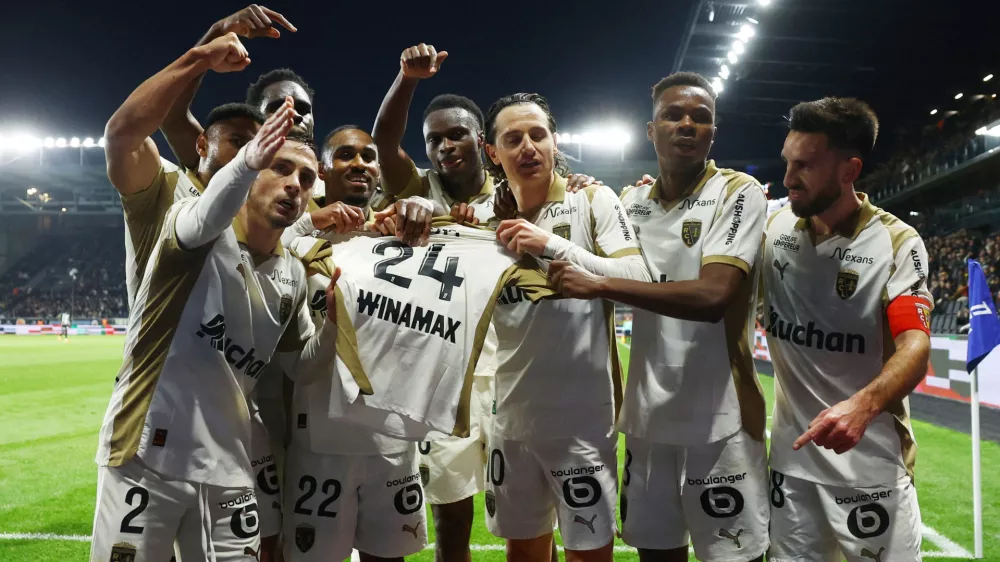 Soccer Football - Ligue 1 - Angers SCO v RC Lens - Stade Raymond Kopa, Angers, France - November 30, 2025 RC Lens' Florian Thauvin celebrates scoring their first goal with teammates by holding up Jonathan Gradit's shirt REUTERS/Stephane Mahe   TPX IMAGES OF THE DAY