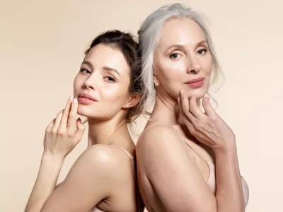 Elderly and young women with smooth skin and natural makeup standing back-to-back. Thinking, planning, dreaming