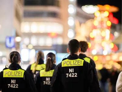 03 December 2025, Lower Saxony, Hanover: Police officers walk through the city center in front of the Christmas pyramid at Kroepcke. German Christmas markets are massively arming themselves after attacks in previous years. Photo: Julian Stratenschulte/dpa