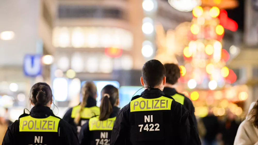 03 December 2025, Lower Saxony, Hanover: Police officers walk through the city center in front of the Christmas pyramid at Kroepcke. German Christmas markets are massively arming themselves after attacks in previous years. Photo: Julian Stratenschulte/dpa