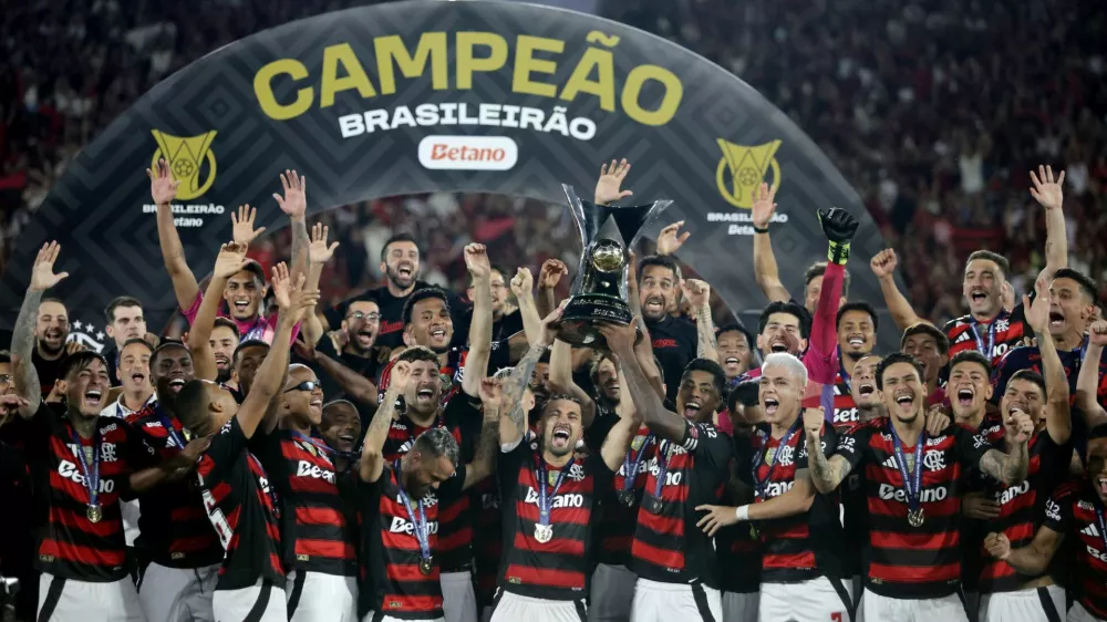 Soccer Football - Brasileiro Championship - Flamengo v Ceara - Estadio Maracana, Rio de Janeiro, Brazil - December 3, 2025 Flamengo's Giorgian de Arrascaeta and Bruno Henrique lift the trophy as they celebrate with teammates after winning the Brasileiro Championship REUTERS/Ricardo Moraes