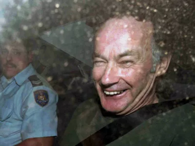 ﻿FILE - In this Nov. 4, 1997, file photo, Ivan Milat smiles in a police car after attending a court in Sydney, Australia. Milat, whose grisly serial killings of young backpackers horrified Australians in the early '90s, died in a Sydney prison on Sunday, Oct. 27, 2019, prison authorities said. He was 74. (AP Photo/Rick Rycroft, File)