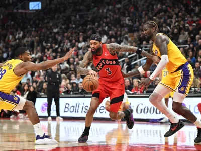 Dec 4, 2025; Toronto, Ontario, CAN; Toronto Raptors forward Brandon Ingram (3) dribbles the ball between Los Angeles Lakers forward Rui Hachimura (28) and center Deandre Ayton (5) in the second half at Scotiabank Arena. Mandatory Credit: Dan Hamilton-Imagn Images
