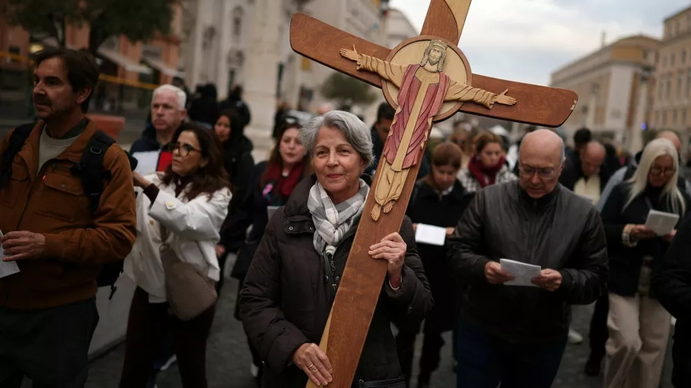 A pilgrim carries a cross near Saint Peter's Square, after a high-level Vatican commission voted against allowing Catholic women to serve as deacons, maintaining the global Church's practice of all-male clergy, according to a report given to Pope Leo and released on Thursday, near the Vatican, in Rome, Italy, December 4, 2025. REUTERS/Guglielmo Mangiapane   TPX IMAGES OF THE DAY