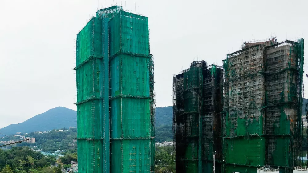 Wang Chi House, the only building not directly affected by the deadly fire at Wang Fuk Court housing complex, stands covered by protective netting, as residents return to the site to fetch their belongings, in Tai Po, Hong Kong, China December 3, 2025. REUTERS/Maxim Shemetov