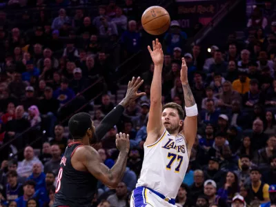Los Angeles Lakers' Luka Doncic, right, shoots the ball against Philadelphia 76ers' Paul George, left, during the first half of an NBA basketball game, Sunday, Dec. 7, 2025, in Philadelphia. (AP Photo/Chris Szagola)