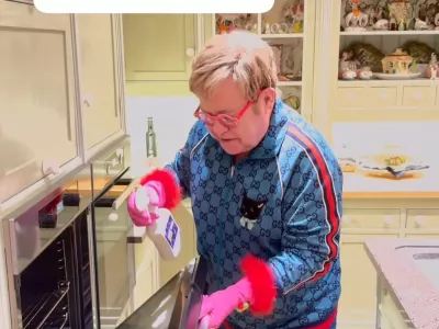 Sir Elton, znan po svojem ekscentričnem slogu oblačenja, je za čiščenje kuhinje oblekel modro trenerko, prekrito z logotipom znamke in mačjim motivom, všitim na sprednji strani. F IG/posnetek zaslona 