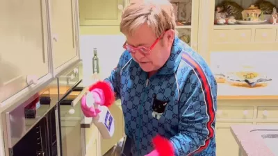 Sir Elton, znan po svojem ekscentričnem slogu oblačenja, je za čiščenje kuhinje oblekel modro trenerko, prekrito z logotipom znamke in mačjim motivom, všitim na sprednji strani. F IG/posnetek zaslona 