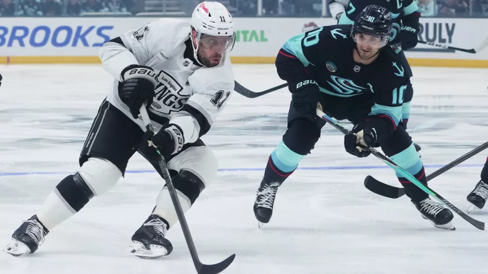 Los Angeles Kings center Anze Kopitar (11) pushes past Seattle Kraken center Matty Beniers (10) during the first period of an NHL hockey game Wednesday, Dec. 10, 2025, in Seattle. (AP Photo/Lindsey Wasson)