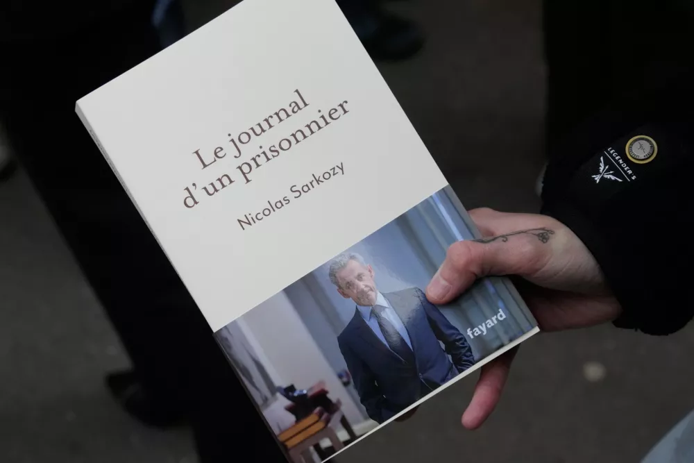 A man holds a book of former French President Nicolas Sarkozy "Diary of a Prisoner," in front a Paris bookshop, Wednesday, Dec. 10, 2025. (AP Photo/Michel Euler)