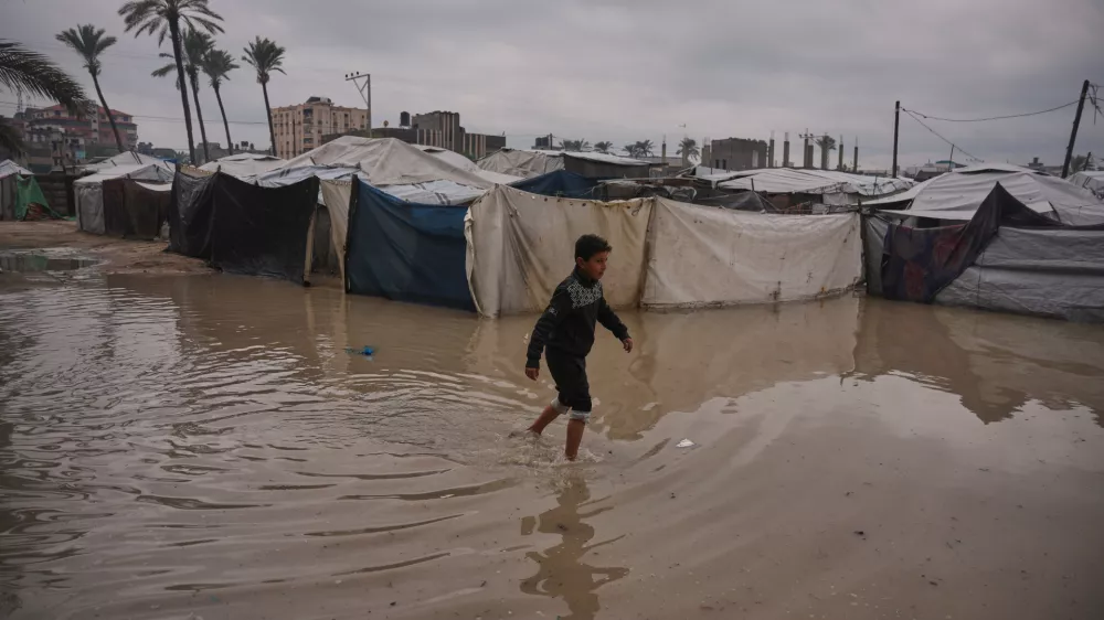A Palestinian youth walks through a flooded area in a temporary tent camp after heavy rainfall in Deir al-Balah, central Gaza Strip, Friday, Dec. 12, 2025. (AP Photo/Abdel Kareem Hana)