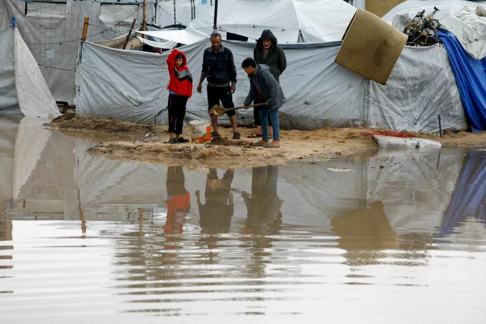 Displaced Palestinians stand near accumulated rainwater as they shelter in a flooded tent camp on a rainy day in Nuseirat, central Gaza Strip, December 12, 2025. REUTERS/Mahmoud Issa   TPX IMAGES OF THE DAY
