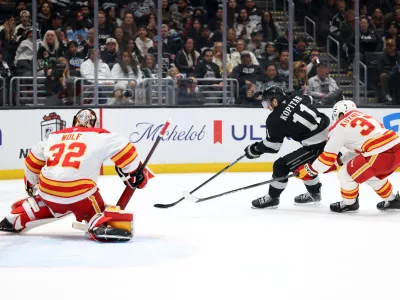 Dec 13, 2025; Los Angeles, California, USA; Los Angeles Kings center Anze Kopitar (11) controls the puck against Calgary Flames defenseman Yan Kuznetsov (37) during the second period at Crypto.com Arena. Mandatory Credit: Kiyoshi Mio-Imagn Images