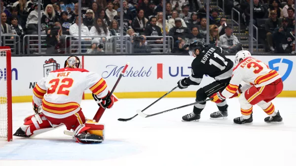 Dec 13, 2025; Los Angeles, California, USA; Los Angeles Kings center Anze Kopitar (11) controls the puck against Calgary Flames defenseman Yan Kuznetsov (37) during the second period at Crypto.com Arena. Mandatory Credit: Kiyoshi Mio-Imagn Images