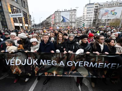 Chairman of the Hungarian opposition Tisza Party Peter Magyar, fifth from left, Vice Chairman of Tisza Party Agnes Forsthoffer, sixth from left, and opera singer Andrea Rost, the party's parliamentary candidate for Jasz-Nagykun-Szolnok County Constituency 1, fourth from right, walk behind a banner reading "Let's protect children" during the Tisza Party demonstration in support of abused children in Budapest, Hungary, Saturday, Dec. 13, 2025. (Robert Hegedus/MTI via AP)