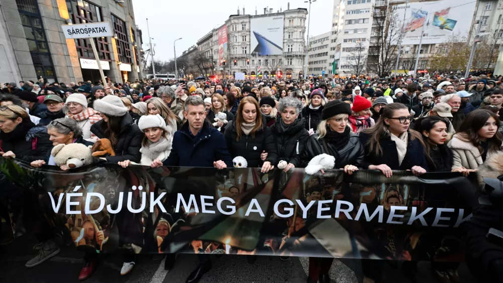 Chairman of the Hungarian opposition Tisza Party Peter Magyar, fifth from left, Vice Chairman of Tisza Party Agnes Forsthoffer, sixth from left, and opera singer Andrea Rost, the party's parliamentary candidate for Jasz-Nagykun-Szolnok County Constituency 1, fourth from right, walk behind a banner reading "Let's protect children" during the Tisza Party demonstration in support of abused children in Budapest, Hungary, Saturday, Dec. 13, 2025. (Robert Hegedus/MTI via AP)