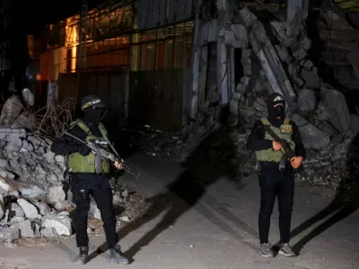 FILE PHOTO: Hamas militants stand guard as Red Cross vehicles (not pictured) transport the bodies of hostages who were held in Gaza since the deadly October 7, 2023, attack, after they were handed over by Hamas militants as part of a ceasefire and a hostage-prisoner swap deal between Hamas and Israel, in Gaza City, October 15, 2025. REUTERS/Dawoud Abu Alkas/File Photo