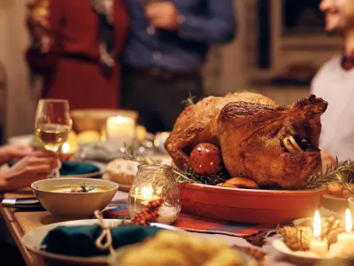 Close up of Thanksgiving turkey on dining table with people in the background.