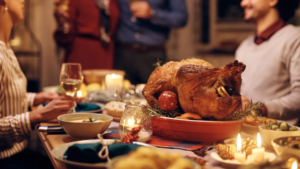 Close up of Thanksgiving turkey on dining table with people in the background.