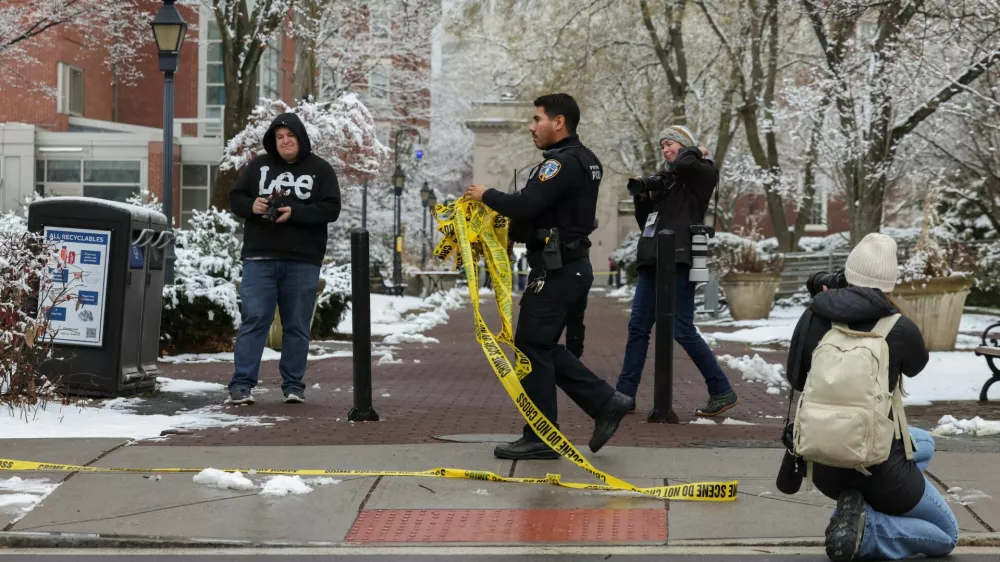 A police officer removes police tape as photographers work around following a shooting at Brown University, in Providence, Rhode Island, U.S. December 14, 2025. REUTERS/Kylie Cooper