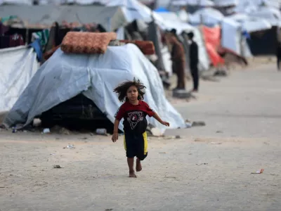 13 December 2025, Palestinian Territories, Gaza CityA Palestinian girl runs between tents during the cold weather. PhotoOmar Ashtawy/APA Images via ZUMA Press Wire/dpa