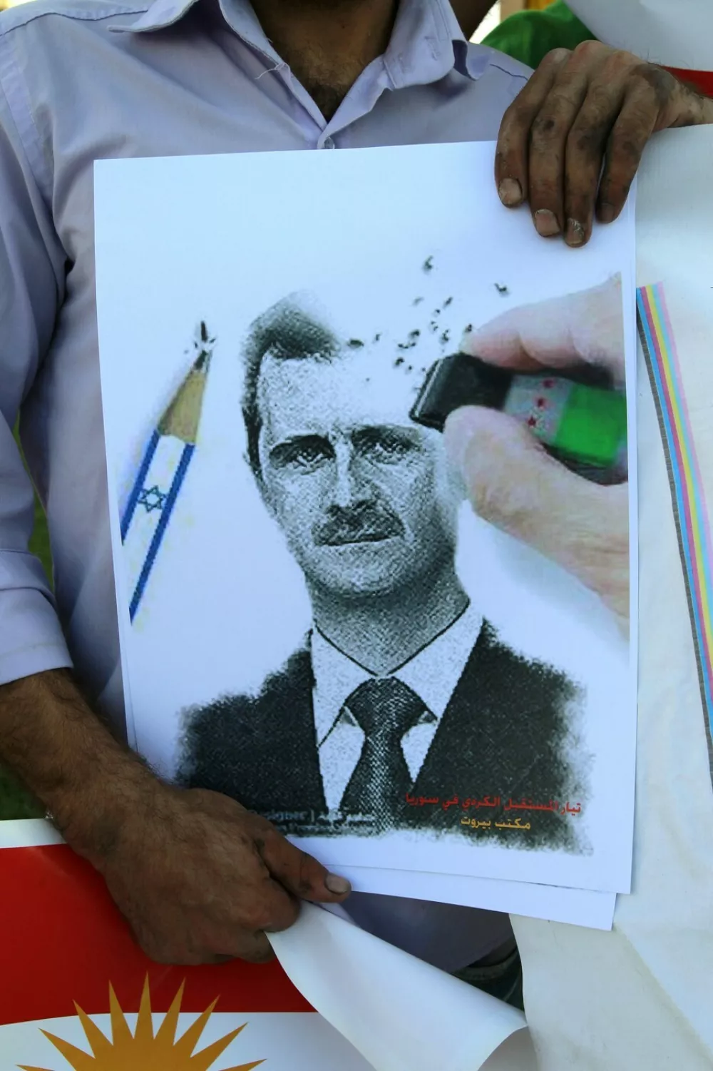 A Syrian Kurd residing in Lebanon holds a placard bearing a portrait of Syrian President Bashar al-Assad, which is drawn with an Israeli flagged pencil and erased with an opposition eraser, during a protest in Beirut on October 7, 2012 to mark the one year anniversary of the assassination of the Syrian Kurdish opposition leader, Meshaal Tamo. Tamo was killed on October 7, 2011, when four masked gunmen stormed his house in Qamishli in northern Syria and opened fire.,Image: 143340157, License: Rights-managed, Restrictions:, Model Release: no
