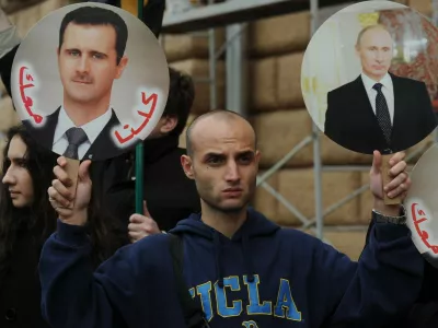 A man holds portrait of Russia's President Vladimir Putin (R) and Syria's President Bashar al-Assad (L) during a rally in support of Syrian regime in front of the US Embassy in Moscow, on October 19, 2012. Moscow has defiantly refused to take sides against Assad, and has slammed the West and Turkey for making clear their support for the rebels battling his regime.,Image: 144327568, License: Rights-managed, Restrictions:, Model Release: no