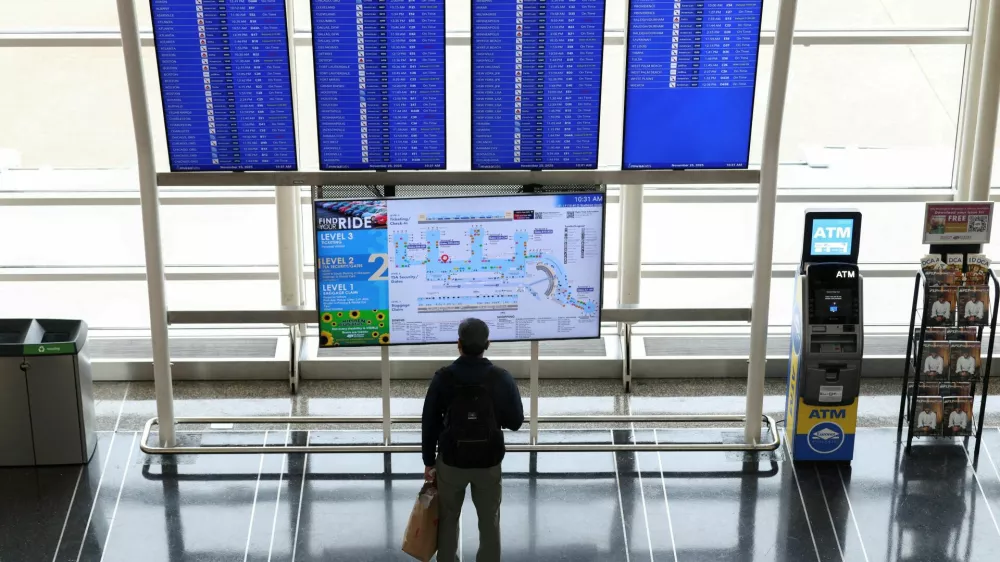 FILE PHOTO: A passenger looks up at a flight information board on the busiest travel day of the Thanksgiving holiday, at Ronald Reagan Washington National Airport in Arlington, Virginia, U.S., November 25, 2025. REUTERS/Kevin Lamarque//File Photo