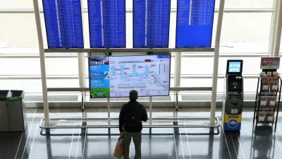 FILE PHOTO: A passenger looks up at a flight information board on the busiest travel day of the Thanksgiving holiday, at Ronald Reagan Washington National Airport in Arlington, Virginia, U.S., November 25, 2025. REUTERS/Kevin Lamarque//File Photo