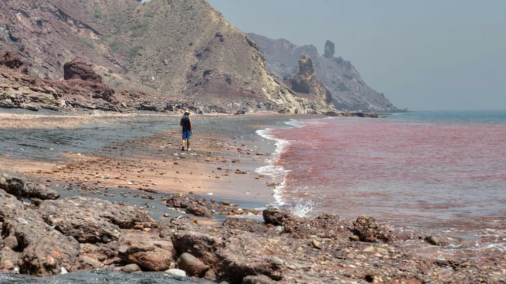 Hormuz Island, Hormozgan Province, Iran - 17 april, 2017: Iranian Island of Hormuz in Persian Gulf, A lonely traveler walks along the red beach along the surf line.,Image: 346861520, License: Royalty-free, Restrictions:, Model Release: no