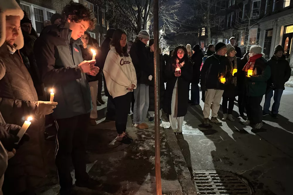 A crowd of people holding candles gather outside the home of Massachusetts Institute of Technology professor Nuno F.G. Loureiro in Brookline, Mass., Tuesday, Dec. 16, 2025. (AP Photo/Leah Willingham)